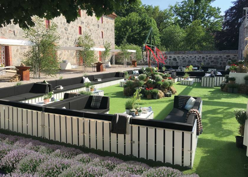 Versatile outdoor tent rental setup with lounge seating and garden decor for events.