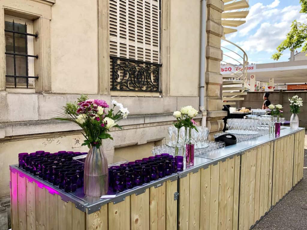 Elegant outdoor beverage station with floral centerpieces and glassware setup for events.