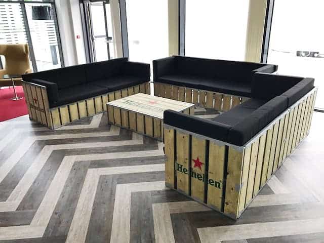 Wooden pallet-style outdoor lounge furniture with black cushions for event seating.