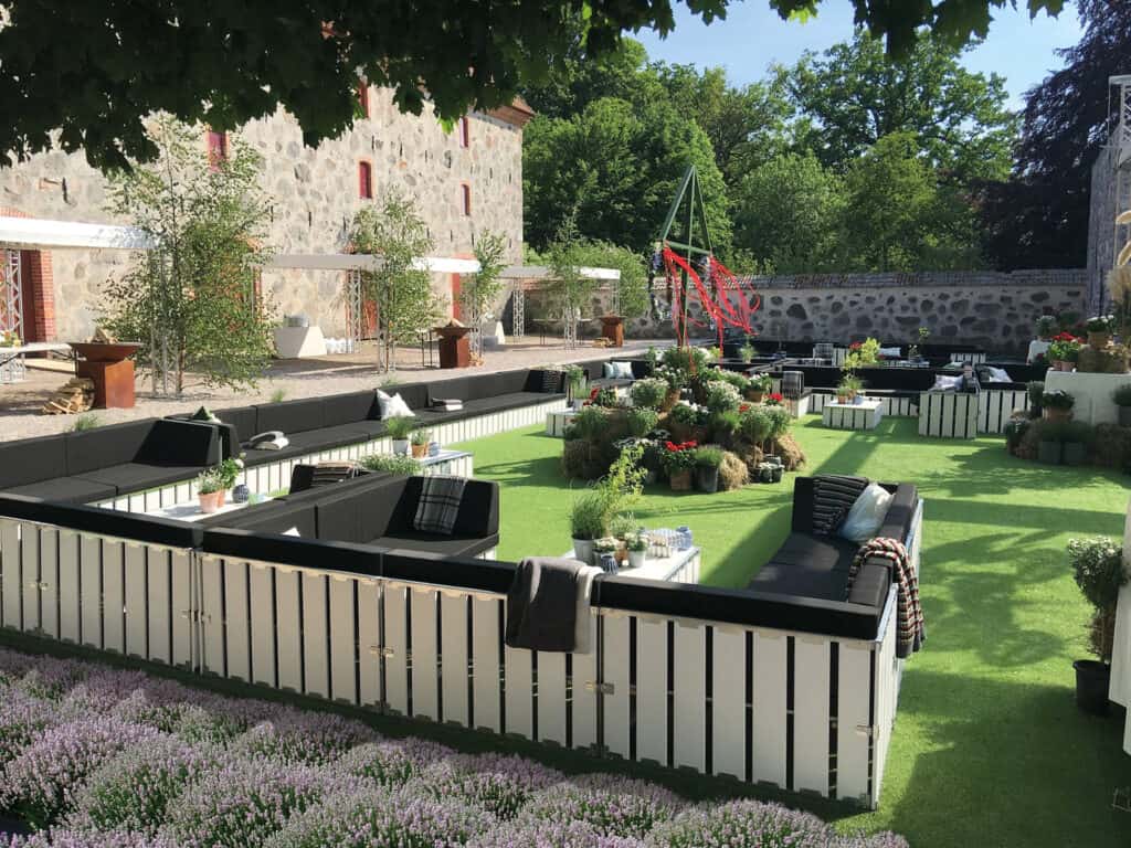 Stylish outdoor event space with modern seating, lush greenery, and vibrant flowers for special occasions.
