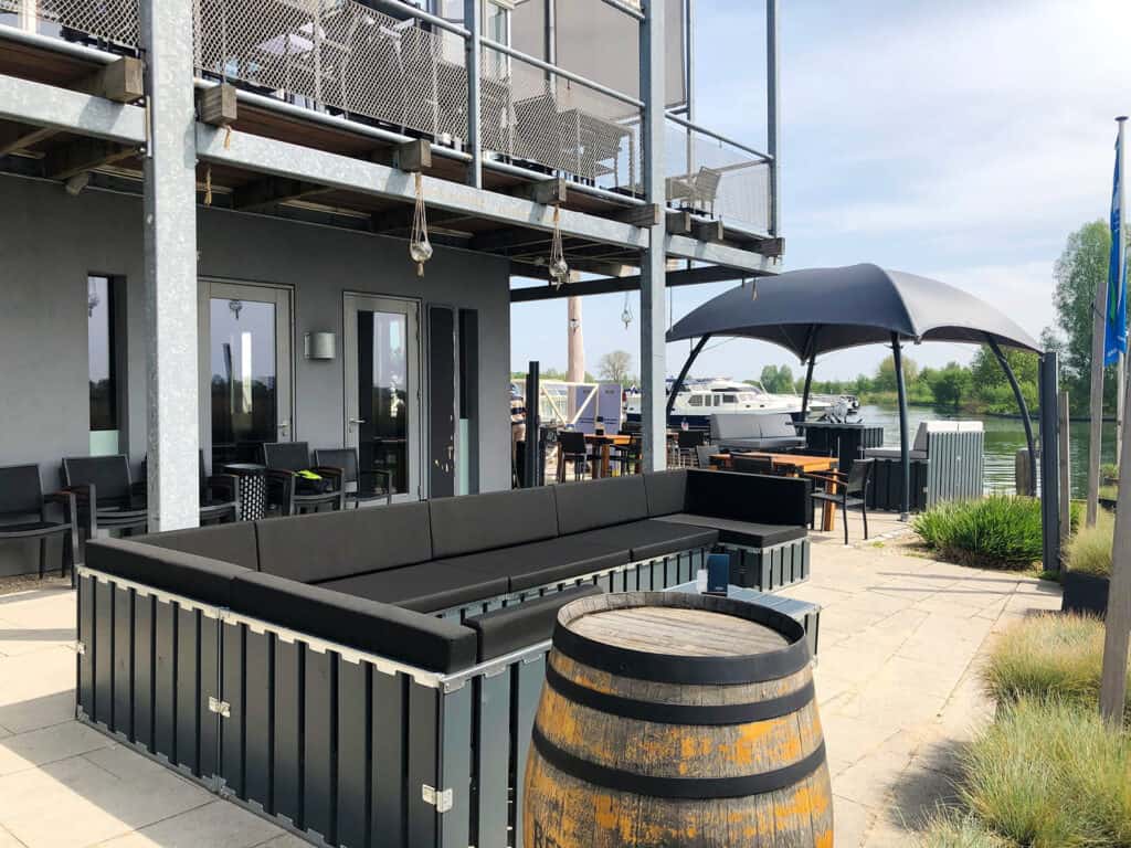 Modern outdoor patio with waterfront view, stylish seating, and shade umbrellas, ideal for events and gatherings.