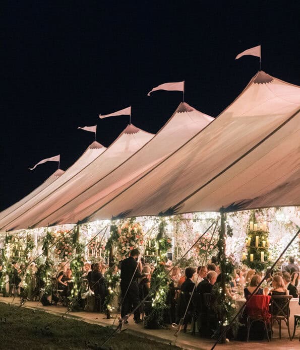 Elegant outdoor wedding tent with floral decor and evening lighting for special events.