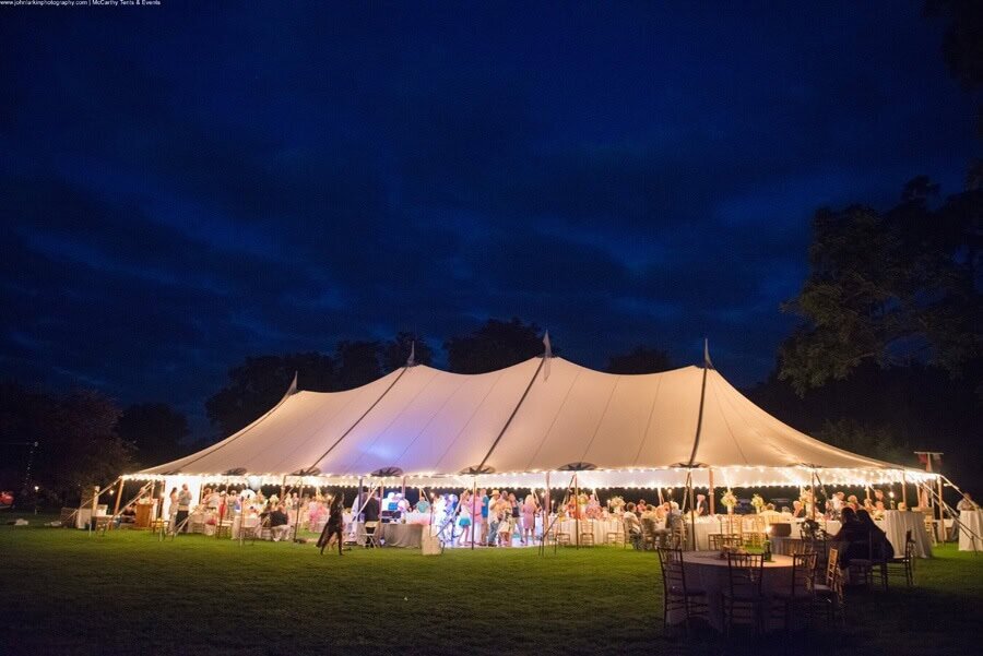 Luxury event tent for outdoor celebrations, illuminated at night.