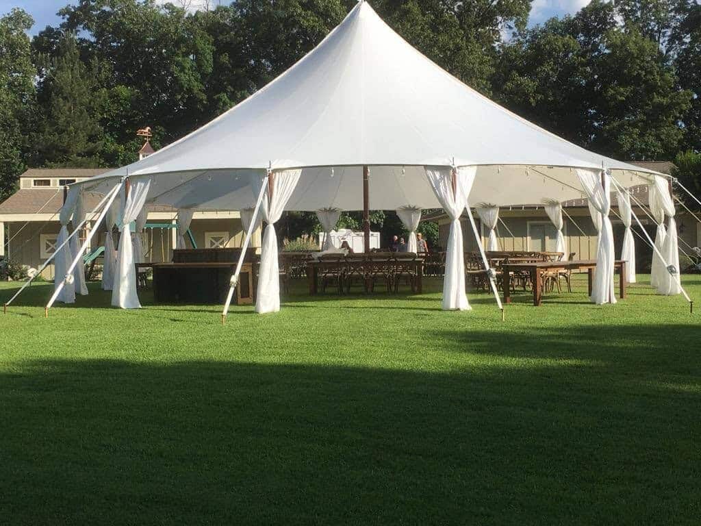 Elegant white event tent setup for outdoor weddings or celebrations, featuring spacious interior with furniture and decor.