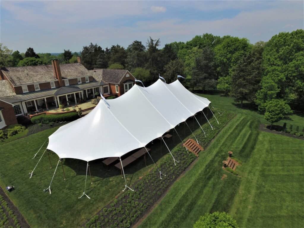 Elegant white event tent set up on lush green lawn for outdoor wedding or celebration.