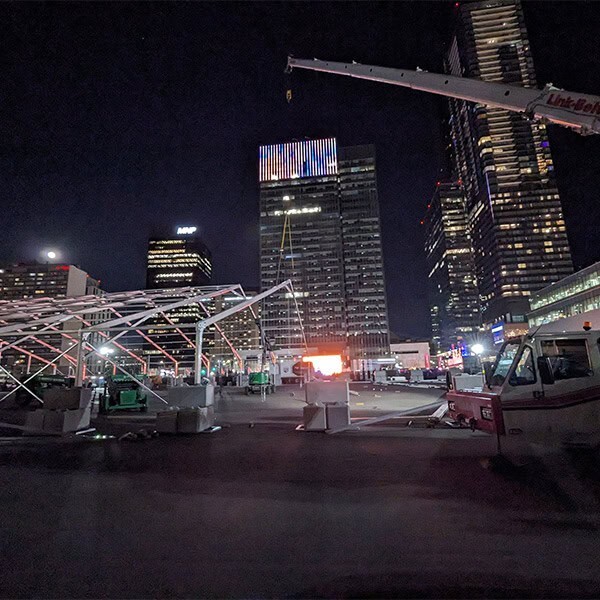 Flexible outdoor event tent rental setup at night in downtown city with tall skyscrapers and lighting, ideal for corporate and special events.