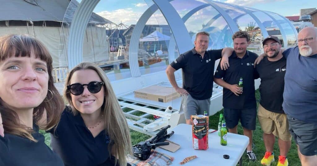 Tent rental event with group of friends enjoying outdoor gathering, superior tent rentals for celebrations and parties, large clear span tent with guests at sunset in backyard.