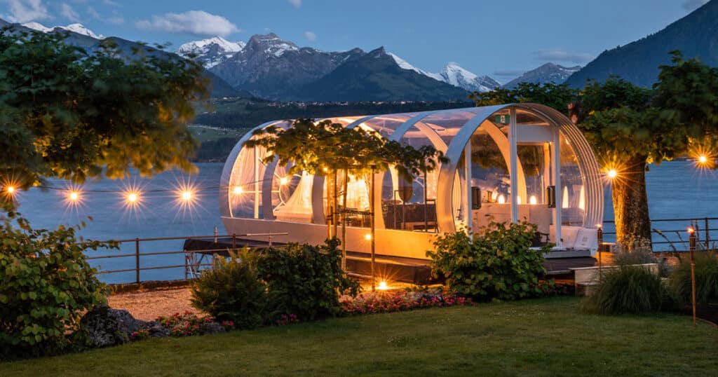 Luxury clear-top lakefront tent with beautiful mountain views at night, perfect for outdoor events.