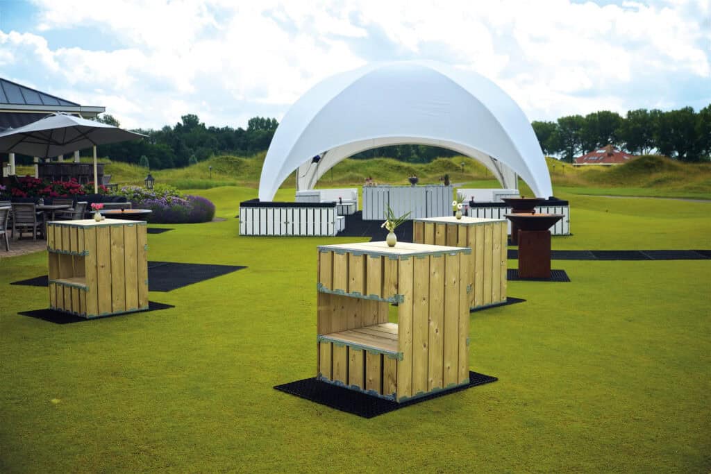 Modern outdoor tent event setup with wooden high-top tables and a white fabric pavilion at Superior Tent Rentals.