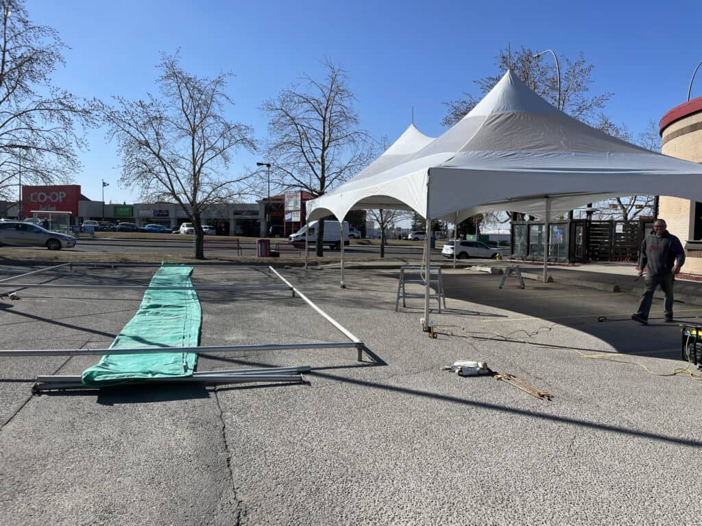 Heavy-duty event tent setup at an outdoor commercial parking lot for tent rental services.
