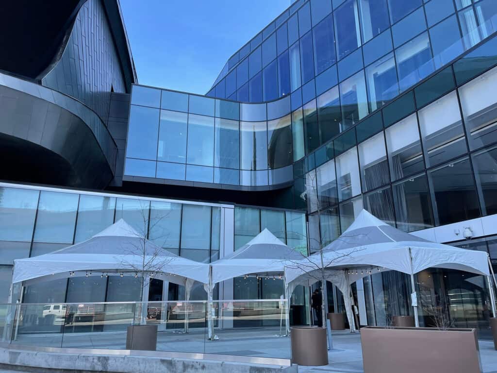 Elegant modern glass building with white event tents for outdoor corporate gatherings.