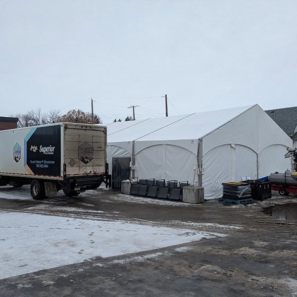 Heavy-duty event tent setup at Superior Tent Rentals with transportation truck on snowy ground, demonstrating durable tent structures for outdoor events or gatherings.