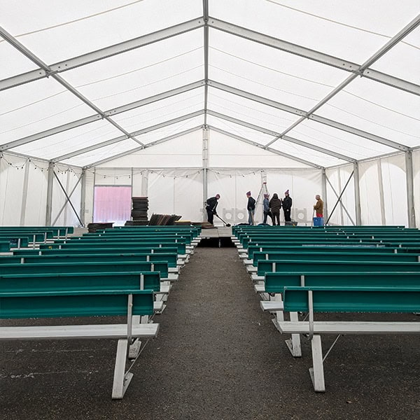 Bright white event tent with teal benches set up for a gathering or ceremony, showcasing superior tent rentals for weddings or special occasions.