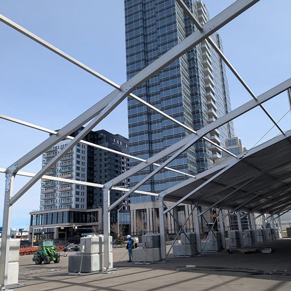 Aluminum framework structure for event tent rental in urban area with high-rise buildings.