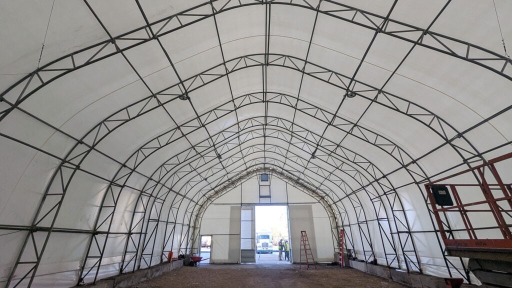 Large temporary event tent with sturdy steel framework and white fabric cover, ideal for weddings, parties, and corporate events from Superior Tent Rentals.